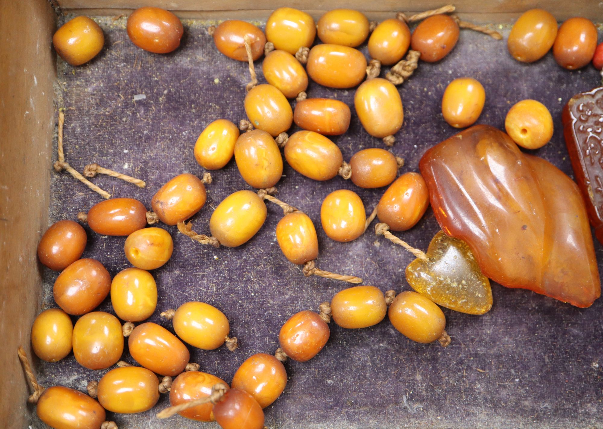 An amber necklace(a.f.) gross 85 grams, four assorted amber pebbles, 528 grams, a carved amber pendant